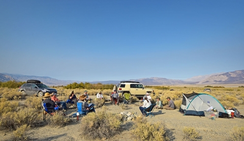 Multiple people sitting on camping chairs in desert