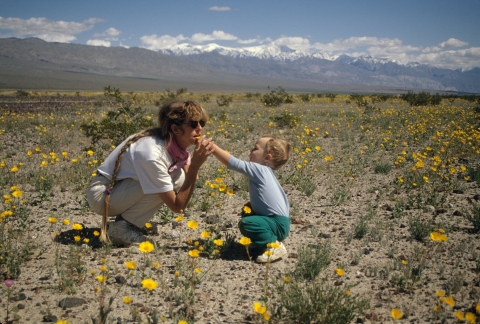 A woman and a small boy crouch in a field of yellow wildflowers
