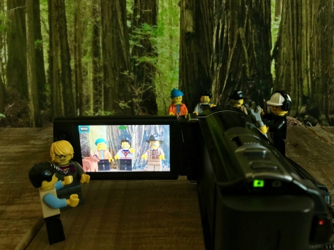 Lego men filming a scene of other lego men working with a camera