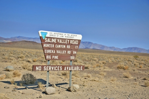 Brown sign with white lettering mounted in desert.
