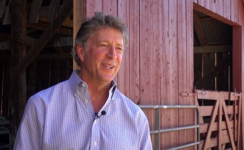 A man in front of a red barn.