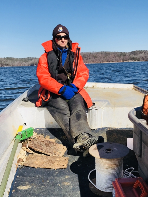 USFWS biologist sitting in a boat on a chilly day