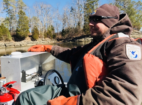 USFWS biologist driving a boat on a chilly day