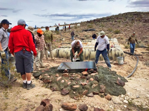 A group helps install a water collection system and trough high on a mountain in the desert