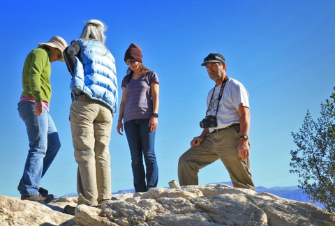 Four people stand in group on a large boulder