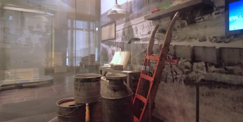 display showing antique milk jugs, barrels, and wooden cart