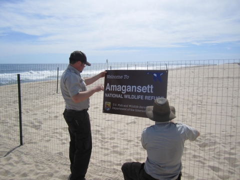 Biologists mount refuge sign on beach fencing