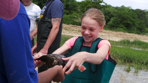 Girl smiles as she holds a diamondback terrapin