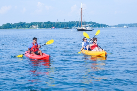 Group of kayakers cross the scenic bay among sailboats