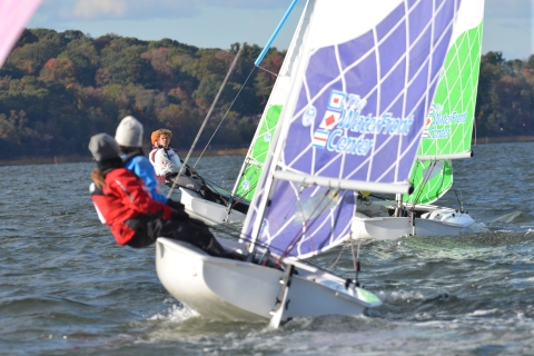 Group of adults chase across the bay in a sailboat