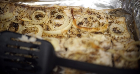 white fish fillet with onions on foil