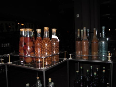 Bottles from the Bertrand with pickled fruits within on glass display shelves. 