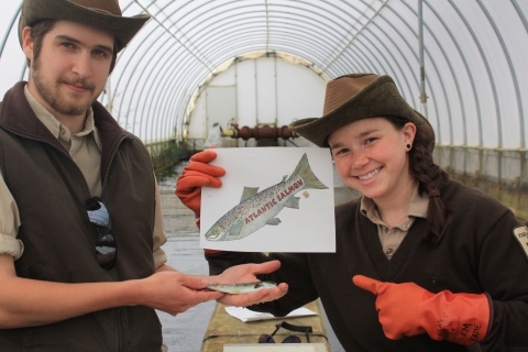 Two biologists holding an illustration of an Atlantic salmon