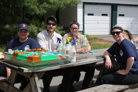 Two biologists and two USFWS volunteers sit at a table during an outreach and education event