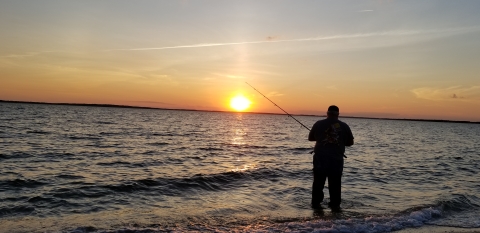 A saltwater angler greets the rising sun while baiting his hook