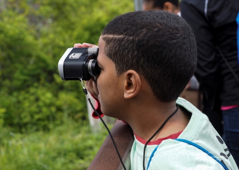Student uses binoculars to look for birds on the refuge