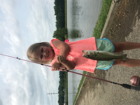 A small child holding a fish just caught.