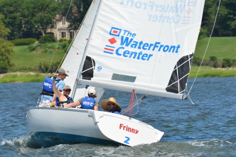 Group of adults chase across the bay in a sailboat