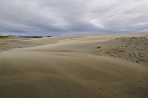 a large sand dune under a cloudy sky.