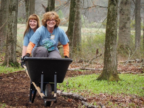 Luann Coen, senior deduction specialist at Brother International, gives a wheelbarrow ride to Miroslawa Gehman, senior deductions manager, at Great Swamp National Wildlife Refuge during a volunteer event at the refuge.