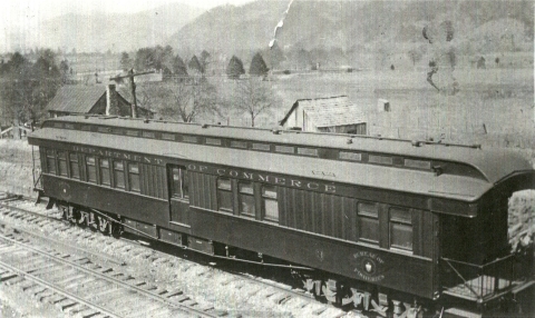 An early 1940's photograph of a single rail car picture on a railroad track with mountains/landscape in the background.