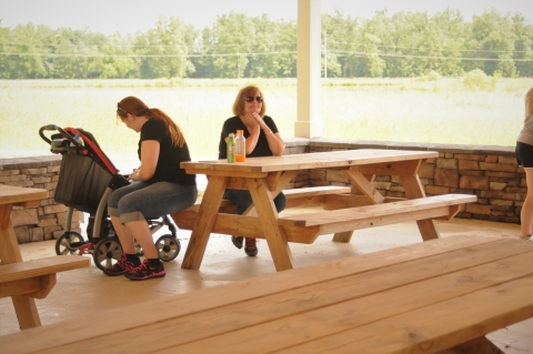 Two people at a picnic table in a covered pavilion.