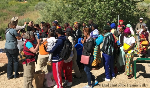 A group of refugees gather to bird watch at the Hyatt Hidden Lakes Reserve