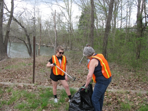 Two volunteers collecting litter along a trail.