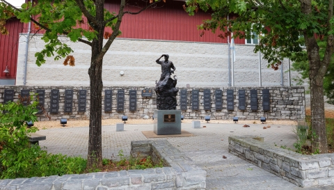 A stone courtyard with a statue in the middle and name plaques on a stone wall