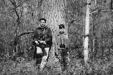 a black and white photo of two people standing next to a tree