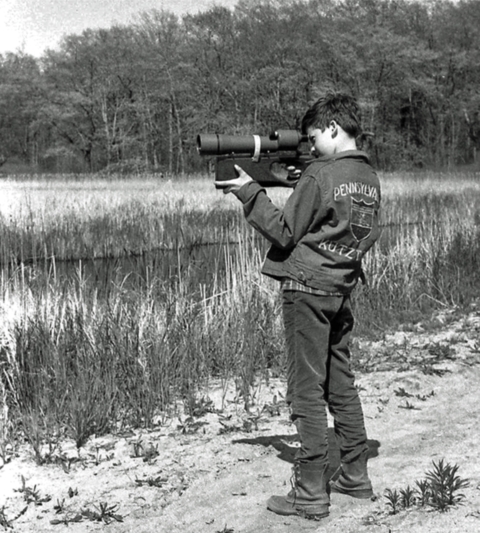 a boy looking through a spotting scope
