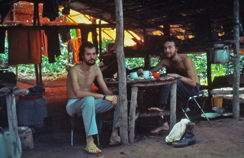 two men sit in a wooden hut