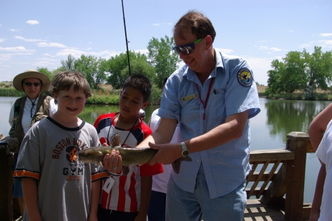 Volunteer angler and kids holding a fish that was caught in Lake Mary
