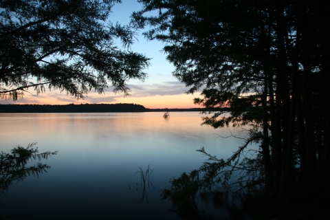 An image of the sun setting over a lake.