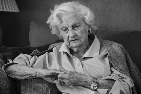 a black and white photo of an elderly woman sitting on a couch