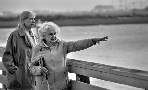 a black and white photo of two woman on a dock