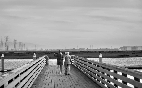 a black and white photo of two woman on a dock