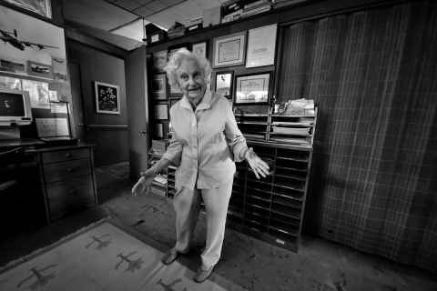 a black and white photo of an elderly woman in an office room