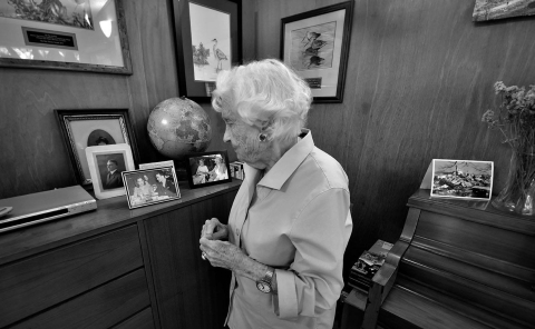 a black and white photo of an elderly woman lookin at photos