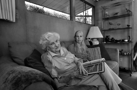 a black and white photo of two women sitting on a couch