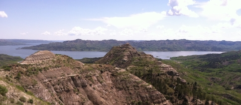 Missouri River Breaks with sparsely vegetated hills in the foreground and Missouri River in background