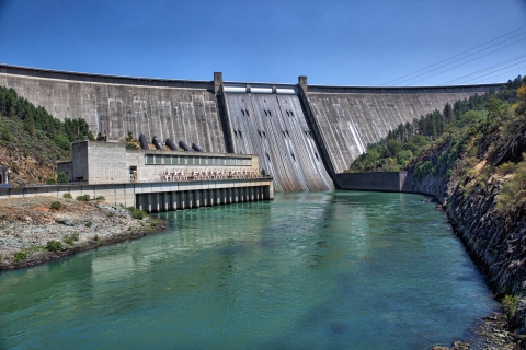 A tall concrete dam with water in the foreground