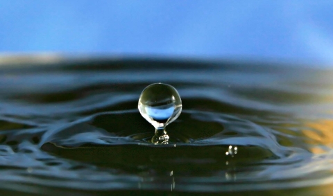  A droplet of water falling into a body of water and causing ripples