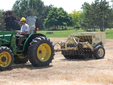 A man on a construction vehicle driving in an empty field
