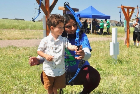 Boy tries archery with assistance from the Groundwork Denver team