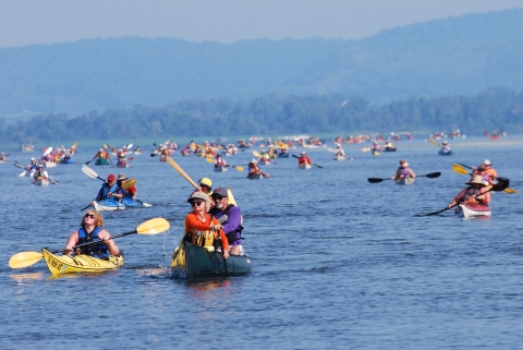 Participants in the annual Great River Rumble paddle their canoes and kayaks along the Mississippi river