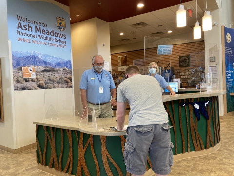 Front desk of visitor center, two volunteers helping a visitor