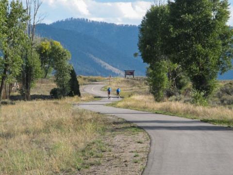 Two cyclists on a paved path through a mostly open area