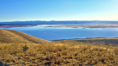 Looking from a high, dry hill onto a body of water in the distance.