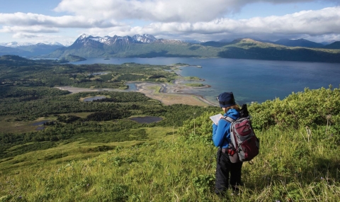 woman standing on hill overlooking view of lake on refuge